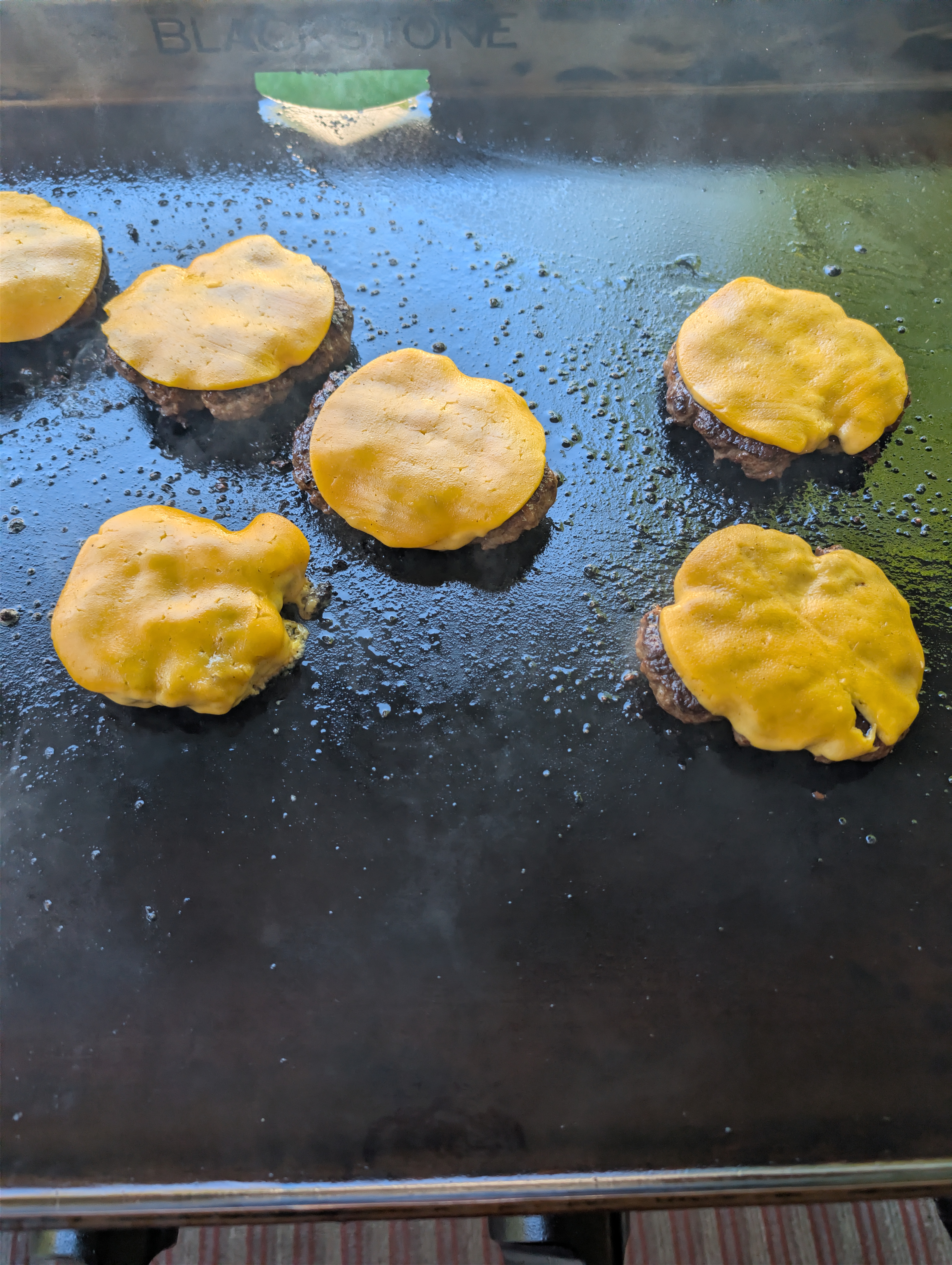 Cheeseburgers melting on a Blackstone griddle