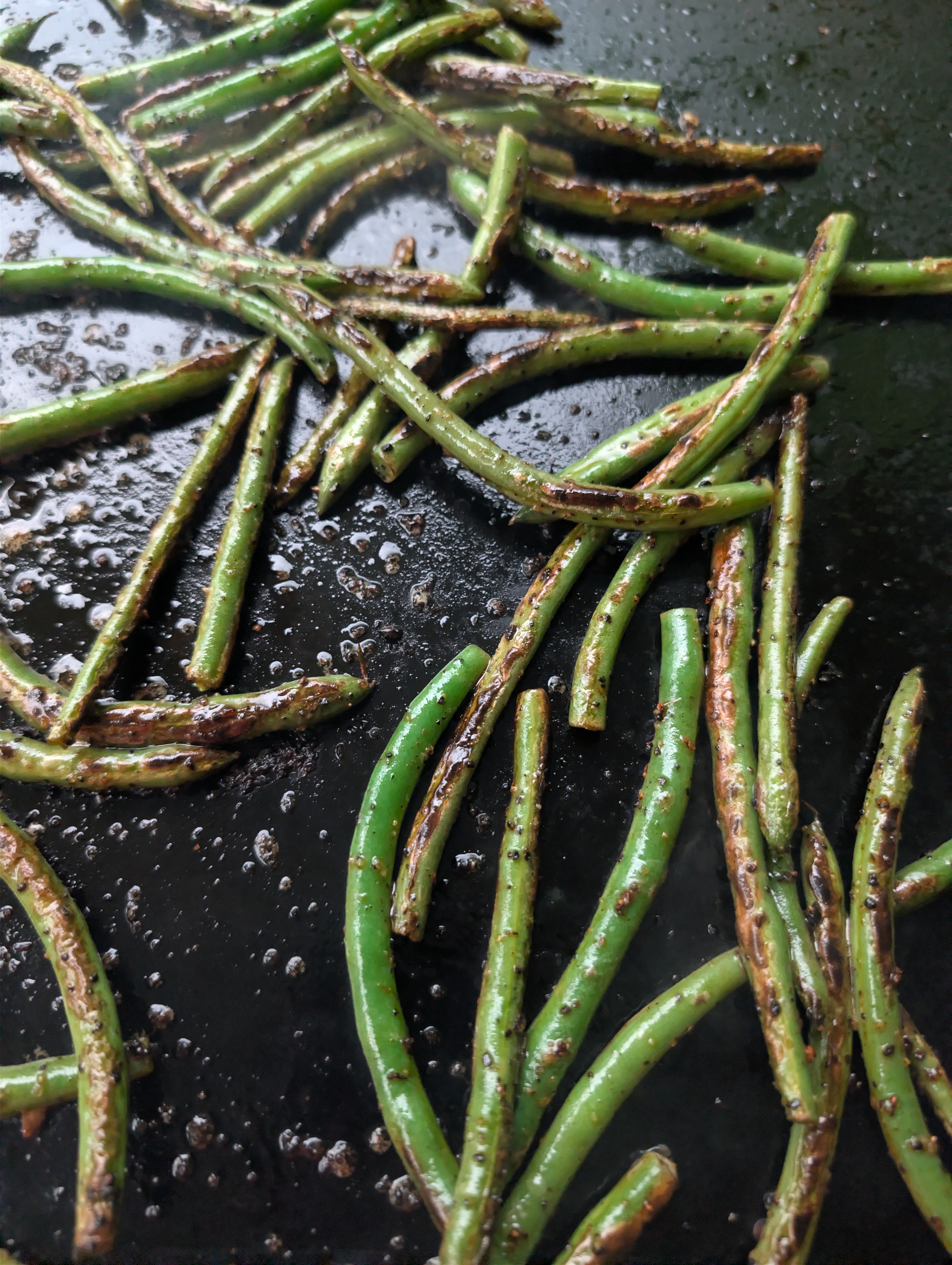 Green beans cooking on a hot Blackstone griddle