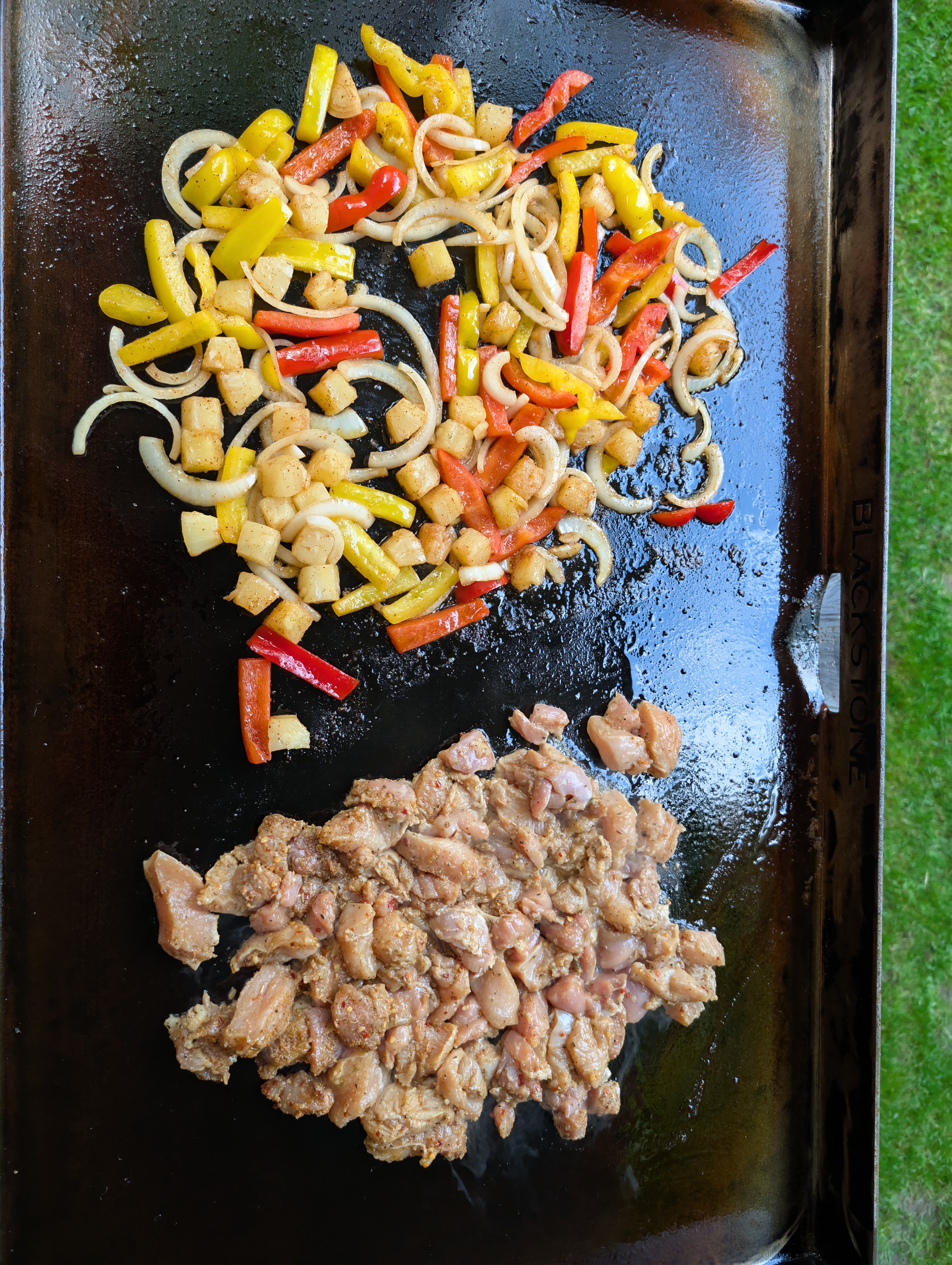 Overhead view of the Blackstone griddle showing vegetables on one side and marinated chicken on the other