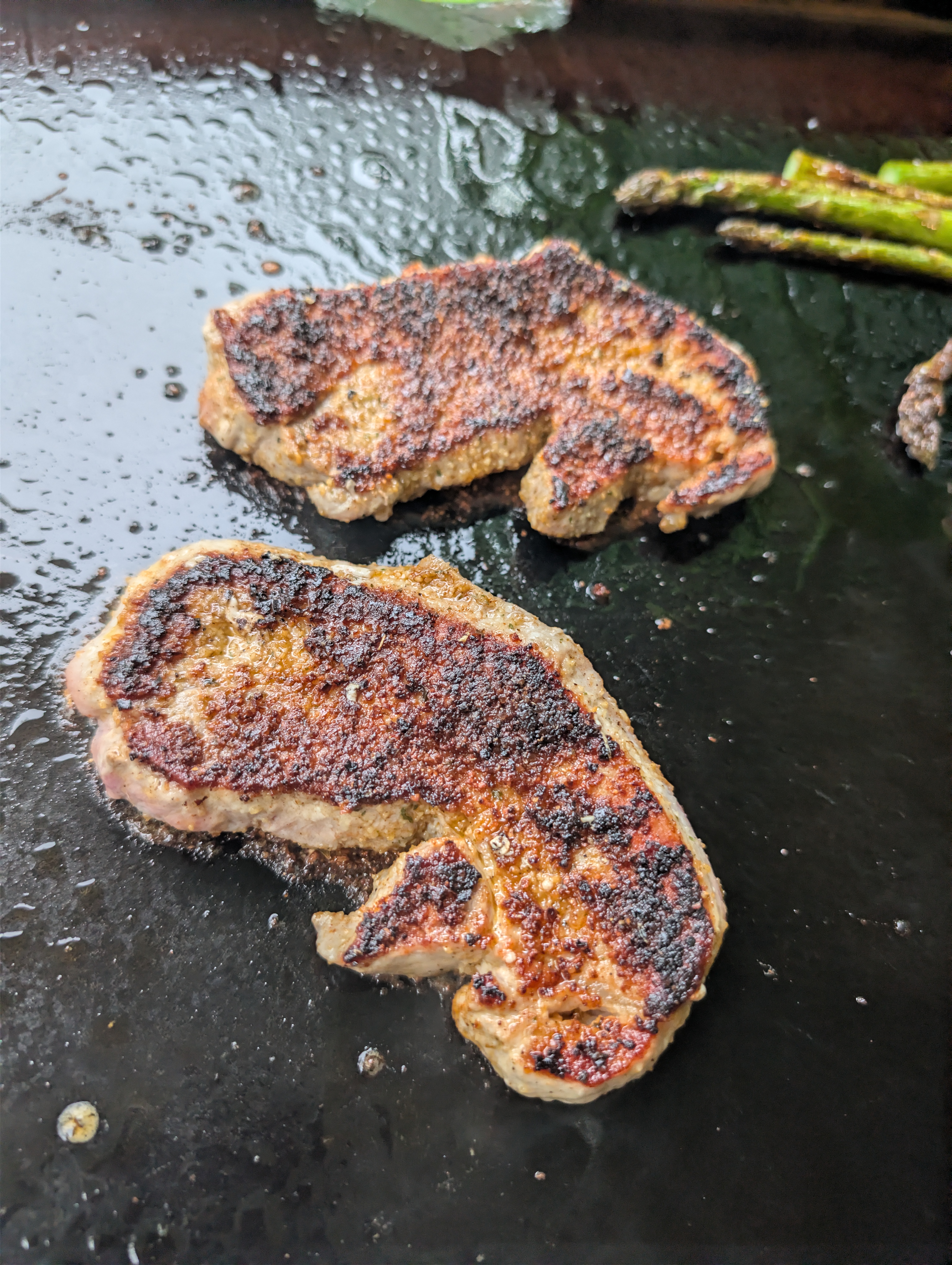 Cajun-seasoned pork steaks with a deep crust, ready to come off the Blackstone griddle